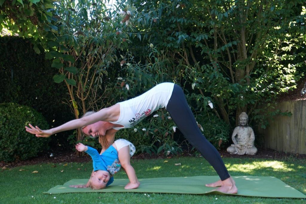 Yoga Personal Trainerin aus Frankfurt übt Postnatal Yoga mit Kind im Garten Teaser