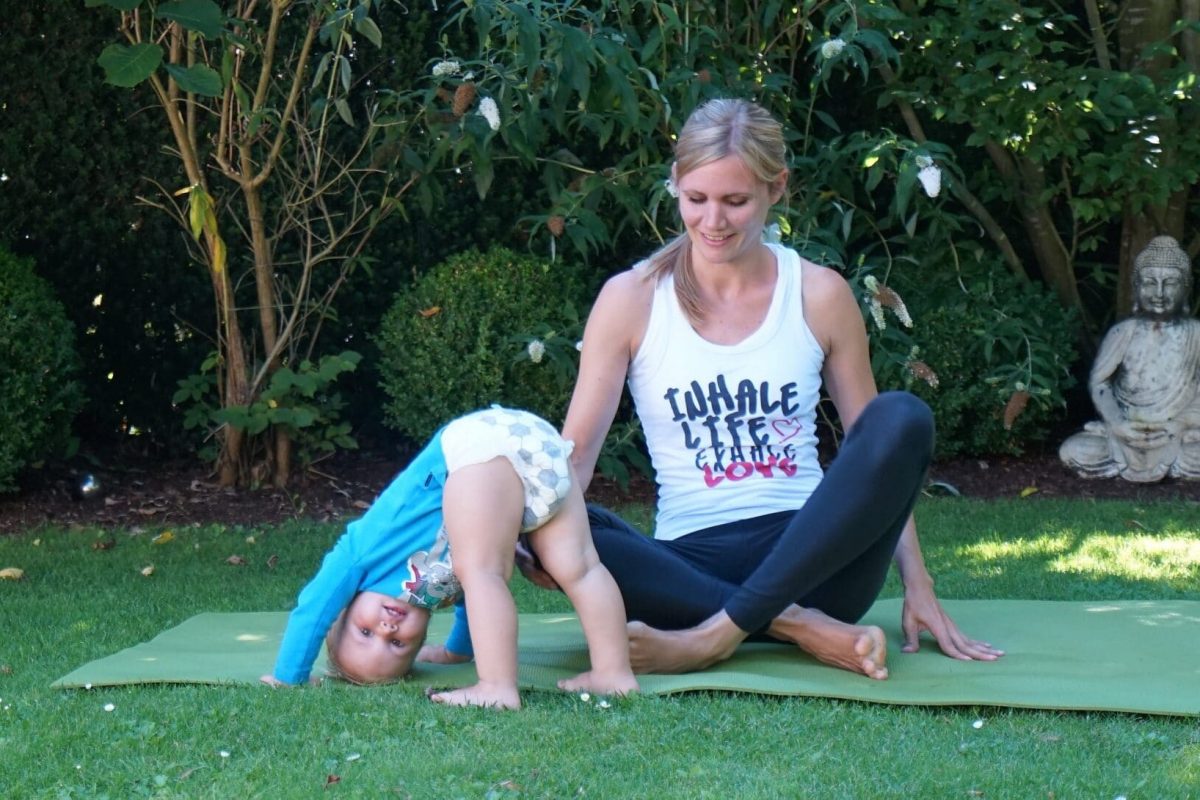 Yoga Personal Trainerin aus Frankfurt macht Yoga nach Geburt zusammen mit Kind im Garten Hero